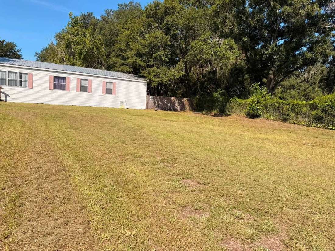 After: evenly mowed lawn along the side of the white home