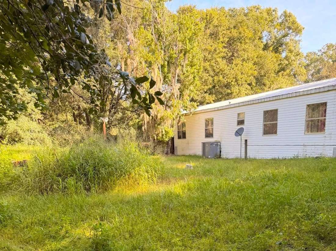 Before: tall overgrown grass beside a white home